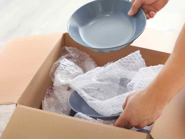 An organizer unpacking a box of dishes during an organized move into a new home, carefully setting up the kitchen for a smooth and efficient move-in.